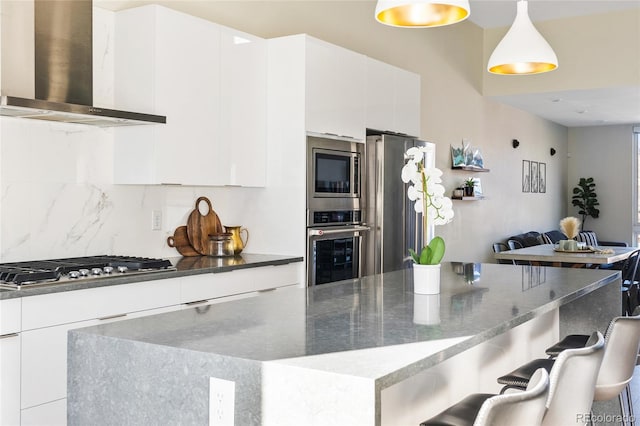 5125 W 29th Ave Unit 5, Denver, CO 80212 - kitchen featuring wall chimney exhaust hood, modern cabinets, appliances with stainless steel finishes, and decorative backsplash