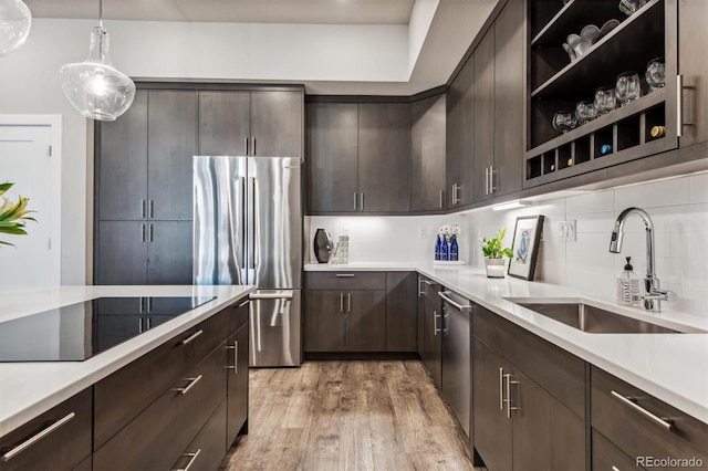 kitchen with pendant lighting, dark brown cabinets, stainless steel appliances, and light hardwood / wood-style floors