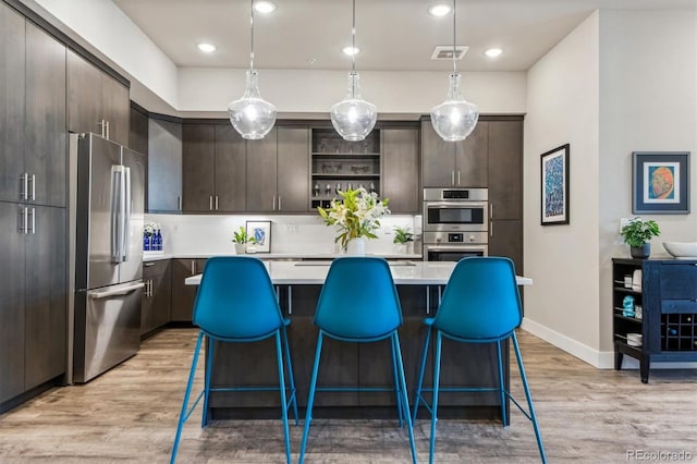 kitchen featuring hanging light fixtures, stainless steel appliances, and dark brown cabinets