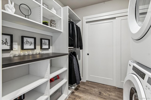 laundry room with hardwood / wood-style floors and stacked washer and clothes dryer