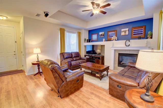 10550 Ashfield St, Highlands Ranch, CO 80126 - living area with a ceiling fan, a tray ceiling, light wood-style floors, and a tiled fireplace