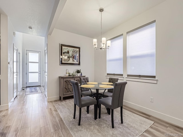 dining space featuring light wood-type flooring, an inviting chandelier, and a healthy amount of sunlight