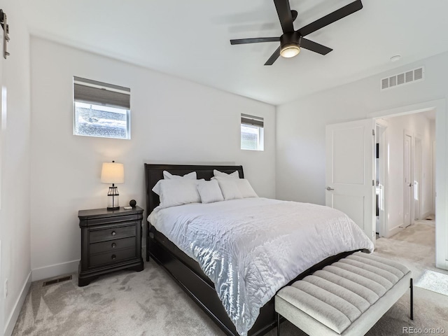 bedroom featuring ceiling fan, light carpet, and multiple windows