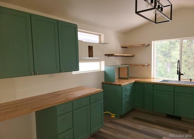 kitchen featuring a healthy amount of sunlight, butcher block counters, green cabinetry, and a sink