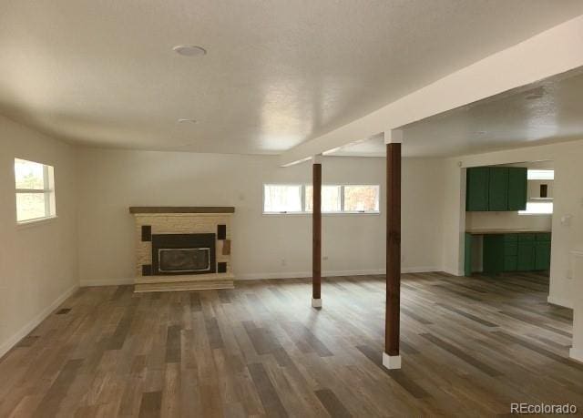 below grade area featuring a fireplace with raised hearth, dark wood-style floors, and baseboards