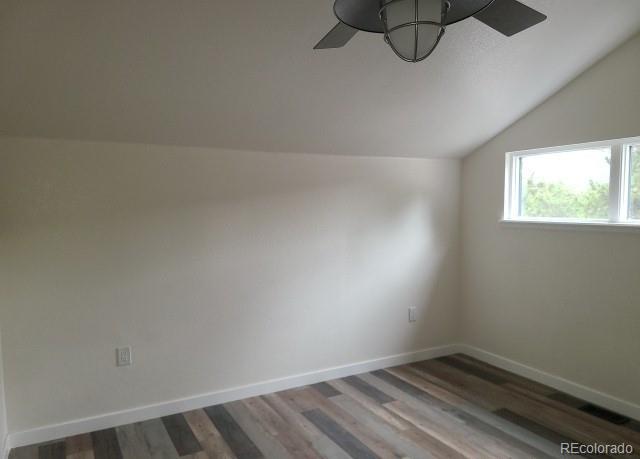 additional living space featuring baseboards, a ceiling fan, vaulted ceiling, and dark wood-type flooring