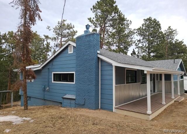 view of side of property featuring a shingled roof and a chimney