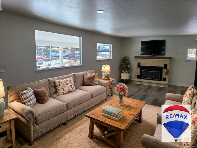 living area with a textured ceiling, a glass covered fireplace, wood finished floors, and baseboards