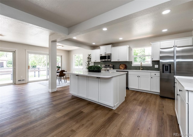 735 Valley Rd, Colorado Springs, CO 80904 - kitchen featuring stainless steel appliances, dark wood-style flooring, a center island, backsplash, and white cabinetry