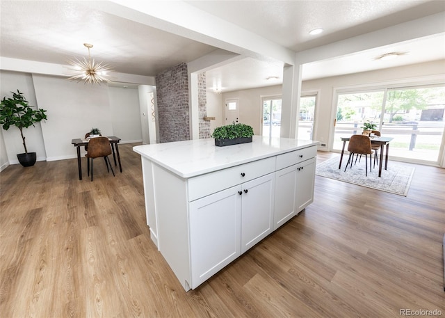 735 Valley Rd, Colorado Springs, CO 80904 - kitchen featuring light wood-style flooring, a center island, white cabinets, a chandelier, and light stone counters