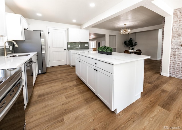 735 Valley Rd, Colorado Springs, CO 80904 - kitchen with a sink, stainless steel appliances, a kitchen island, decorative backsplash, and light wood-style floors