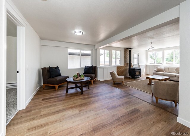 735 Valley Rd, Colorado Springs, CO 80904 - living area featuring a baseboard heating unit, a wood stove, and light wood finished floors