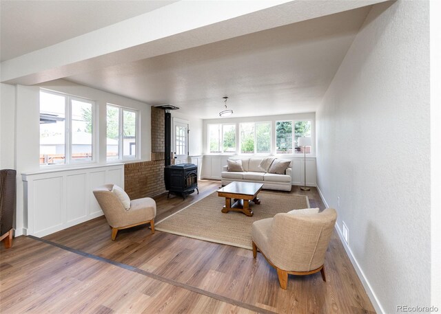 735 Valley Rd, Colorado Springs, CO 80904 - living area featuring a wood stove, wood finished floors, a textured wall, and wainscoting