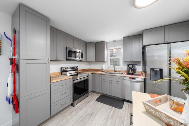 kitchen featuring appliances with stainless steel finishes, sink, gray cabinetry, and decorative light fixtures