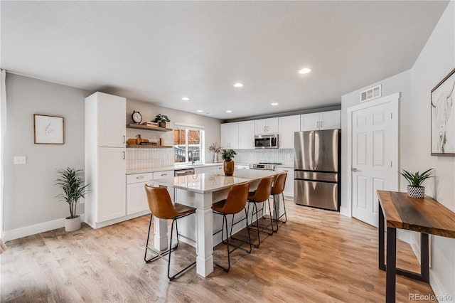 kitchen featuring tasteful backsplash, appliances with stainless steel finishes, a center island, and white cabinets