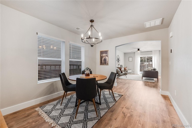 dining space featuring arched walkways, light wood finished floors, visible vents, and baseboards