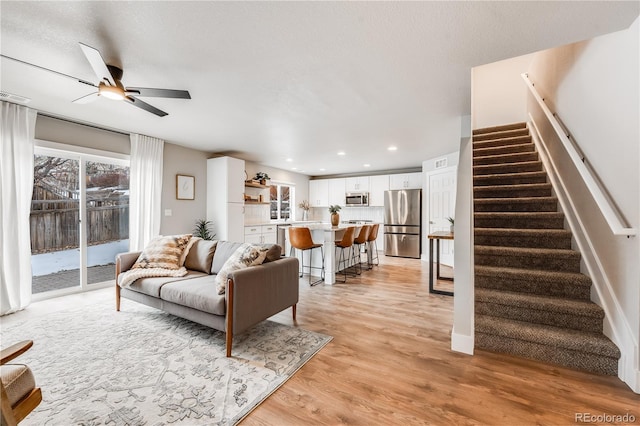 living area featuring visible vents, a ceiling fan, stairway, light wood-style floors, and recessed lighting