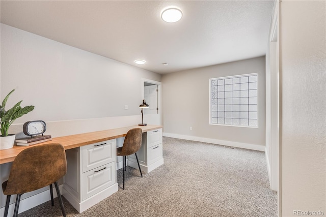 office space with light colored carpet, visible vents, baseboards, and built in study area