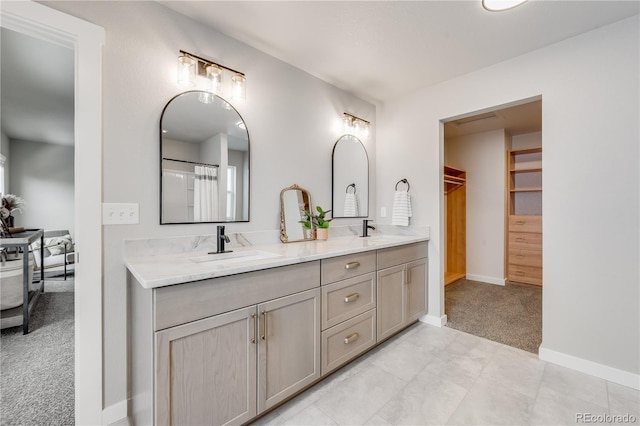 full bathroom featuring double vanity, baseboards, a walk in closet, and a sink