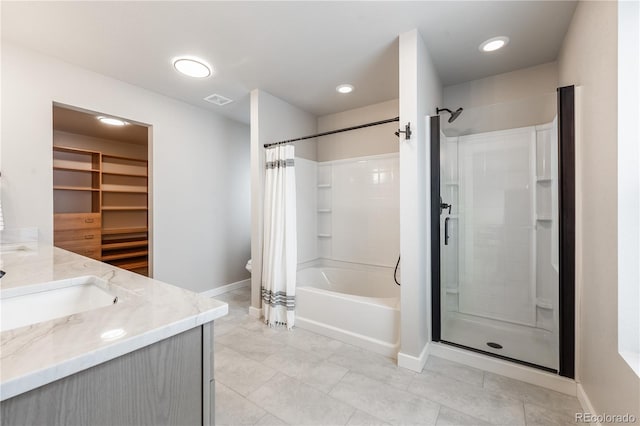 bathroom with a walk in closet, visible vents, vanity, and baseboards