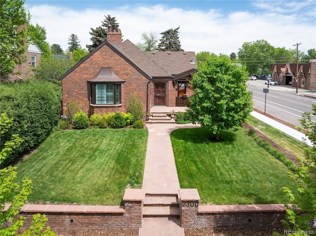 english style home featuring a front yard and brick siding