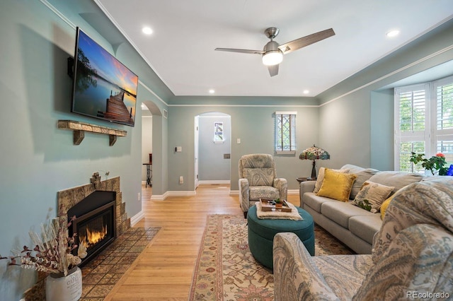 living room featuring arched walkways, healthy amount of natural light, a ceiling fan, light wood-type flooring, and recessed lighting