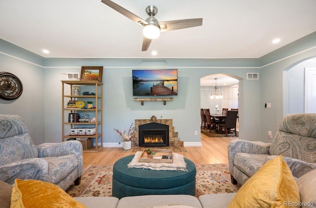 living room with arched walkways, wood finished floors, ceiling fan, a glass covered fireplace, and recessed lighting