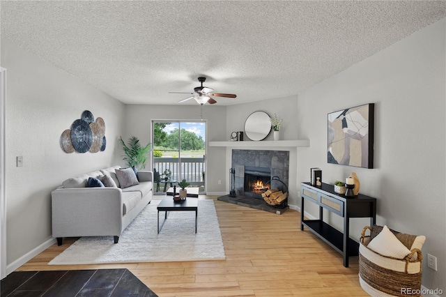 13404 E Jewell Ave Unit 101, Aurora, CO 80012 - living area with ceiling fan, a tiled fireplace, light wood-style floors, and a textured ceiling