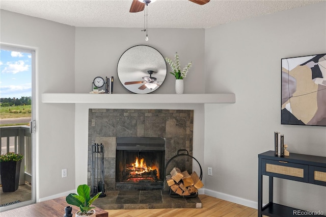13404 E Jewell Ave Unit 101, Aurora, CO 80012 - detailed view of ceiling fan, wood finished floors, a tiled fireplace, and a textured ceiling