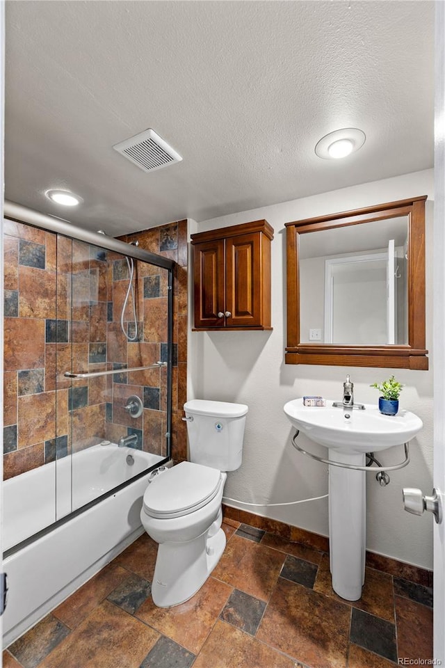 13404 E Jewell Ave Unit 101, Aurora, CO 80012 - bathroom with bath / shower combo with glass door, stone tile floors, and a textured ceiling