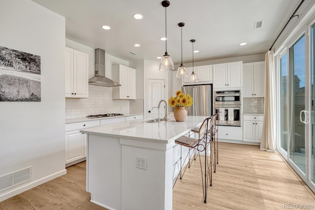 17396 Hop Clover Ave, Parker, CO 80134 - kitchen featuring wall chimney range hood, appliances with stainless steel finishes, decorative backsplash, a breakfast bar, and recessed lighting