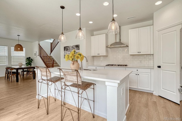 17396 Hop Clover Ave, Parker, CO 80134 - kitchen featuring light wood-type flooring, gas stovetop, tasteful backsplash, light countertops, and a center island with sink