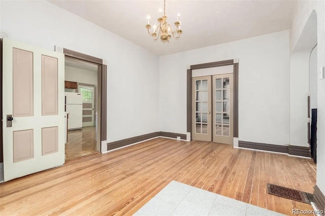 empty room featuring wood-type flooring and a notable chandelier