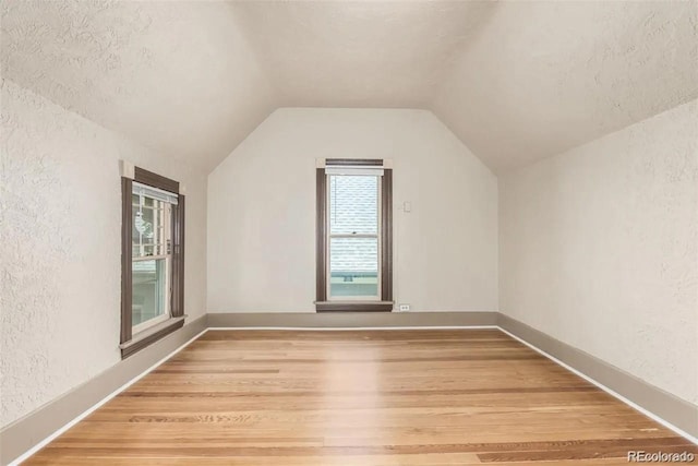 bonus room featuring wood-type flooring, a textured ceiling, and vaulted ceiling