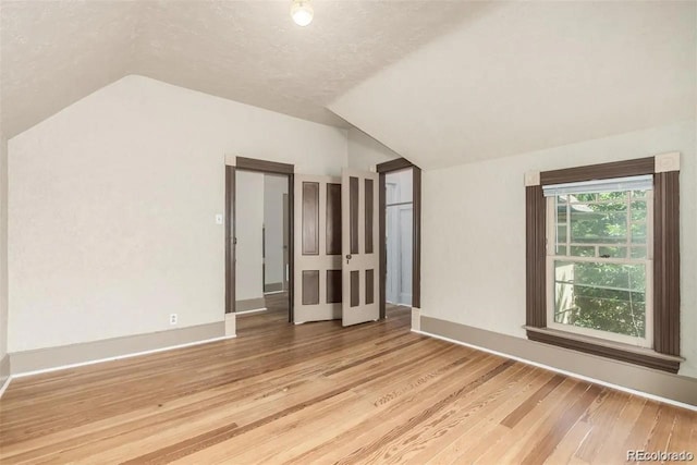 bonus room featuring a textured ceiling, light wood-type flooring, and vaulted ceiling