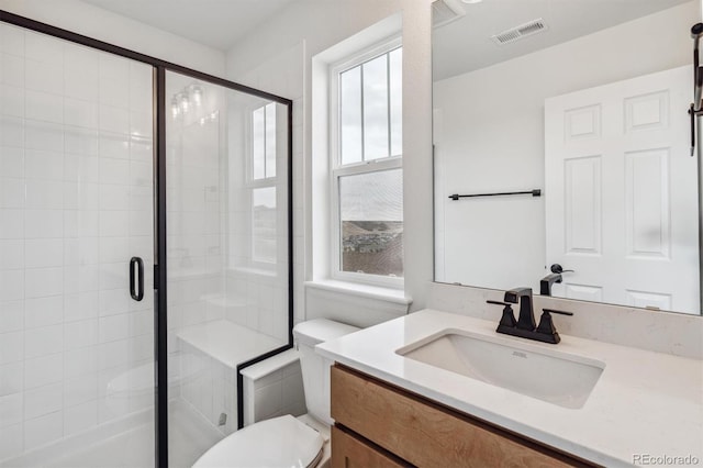 bathroom with vanity, toilet, and a shower with door