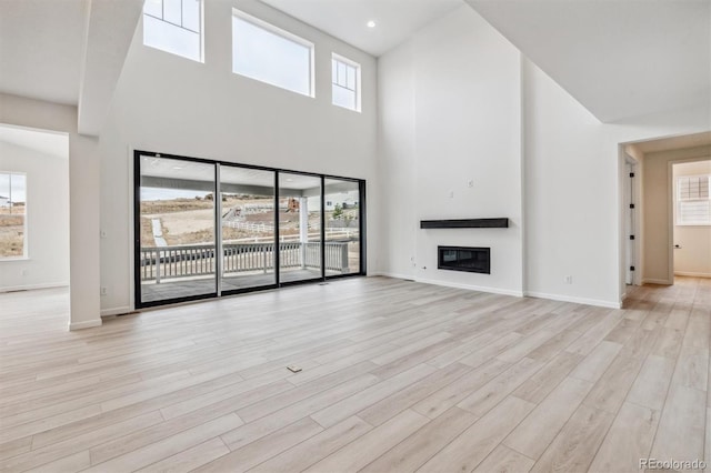 unfurnished living room with a high ceiling and light hardwood / wood-style floors