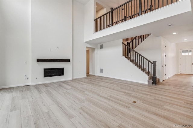 unfurnished living room with a high ceiling and light hardwood / wood-style flooring