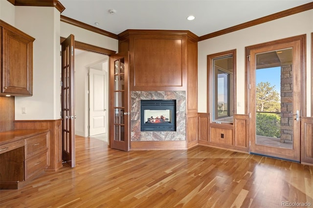606 Cliffgate Ln, Castle Rock, CO 80108 - unfurnished living room with light wood finished floors, ornamental molding, wainscoting, a premium fireplace, and french doors