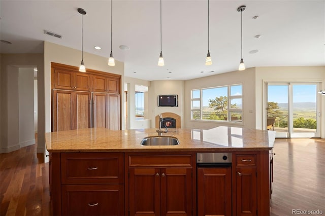 606 Cliffgate Ln, Castle Rock, CO 80108 - kitchen featuring dark wood-style floors, pendant lighting, an island with sink, a lit fireplace, and light stone counters