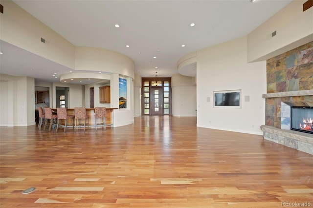 606 Cliffgate Ln, Castle Rock, CO 80108 - unfurnished living room featuring light wood-style flooring, a stone fireplace, recessed lighting, and a high ceiling
