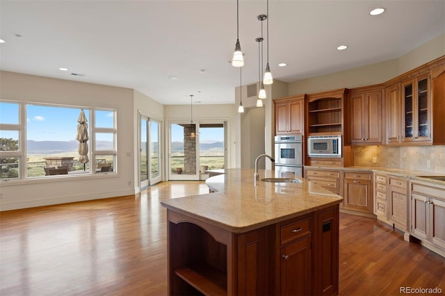606 Cliffgate Ln, Castle Rock, CO 80108 - kitchen with open shelves, stainless steel microwave, dark wood finished floors, backsplash, and a center island with sink