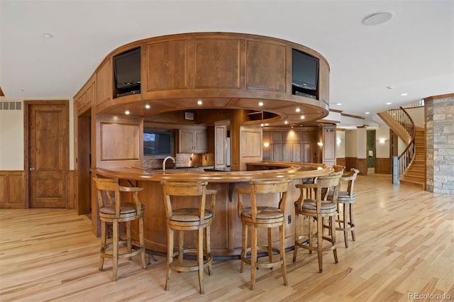 606 Cliffgate Ln, Castle Rock, CO 80108 - bar featuring a wainscoted wall, light wood-style floors, stairs, wood walls, and recessed lighting