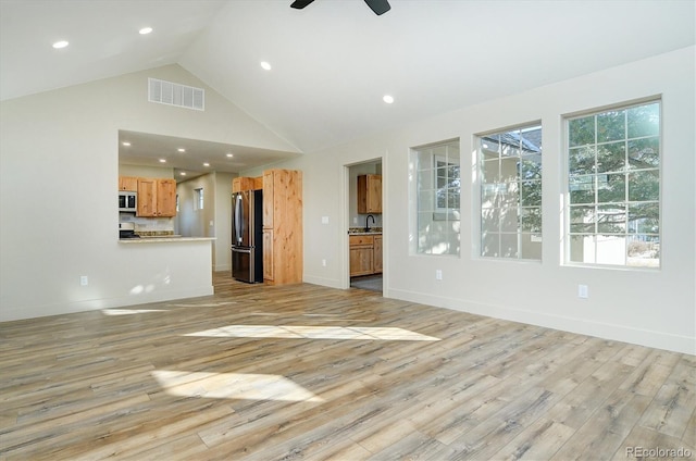 unfurnished living room with ceiling fan, sink, light hardwood / wood-style floors, and high vaulted ceiling