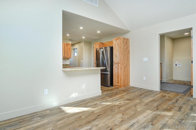 kitchen featuring light brown cabinetry, stainless steel fridge, and light hardwood / wood-style floors