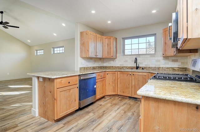 kitchen with light wood-type flooring, light stone counters, kitchen peninsula, stainless steel appliances, and ceiling fan