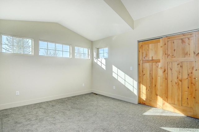 unfurnished bedroom with carpet, a closet, and vaulted ceiling