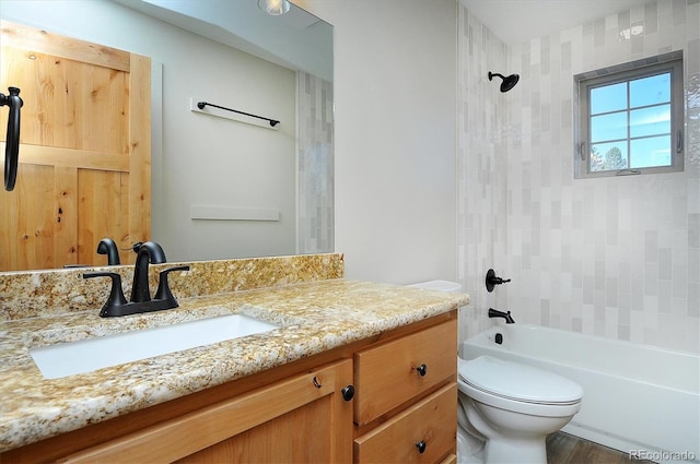 full bathroom featuring vanity, tiled shower / bath combo, and toilet