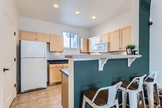 85 Uinta Way Unit 702, Denver, CO 80230 - kitchen featuring white appliances, light brown cabinets, a breakfast bar, tasteful backsplash, and recessed lighting