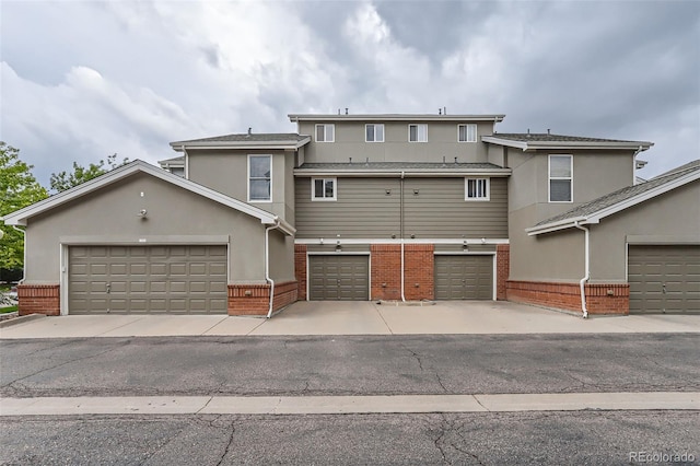 85 Uinta Way Unit 702, Denver, CO 80230 - view of front of home featuring brick siding, stucco siding, an attached garage, and driveway